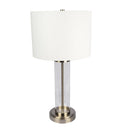 Clear glass table lamp casting warm, ambient light over a cozy reading nook