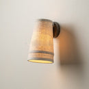 Front view of the minimalist wabi-sabi style iron and linen fabric wall sconce mounted on a textured beige wall
