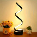 Front view of the modern adjustable USB powered spiral LED desk lamp on a black and white workspace