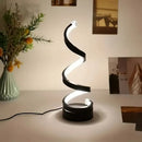 Sleek black spiral LED desk lamp illuminating a contemporary home office desk setup