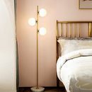 Front view of a modern minimalist gold aluminum alloy and glass LED floor lamp in a living room
