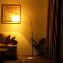 Graceful arc of the fishing floor lamp extending over a comfortable reading chair