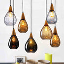 Front view of a Nordic single-head glass chandelier illuminating a modern dining room table