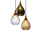 Trio of single-head glass chandeliers installed linearly above a large kitchen island