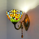 Rich, colorful ambient light filtering through the artisan stained glass shade onto a textured wall